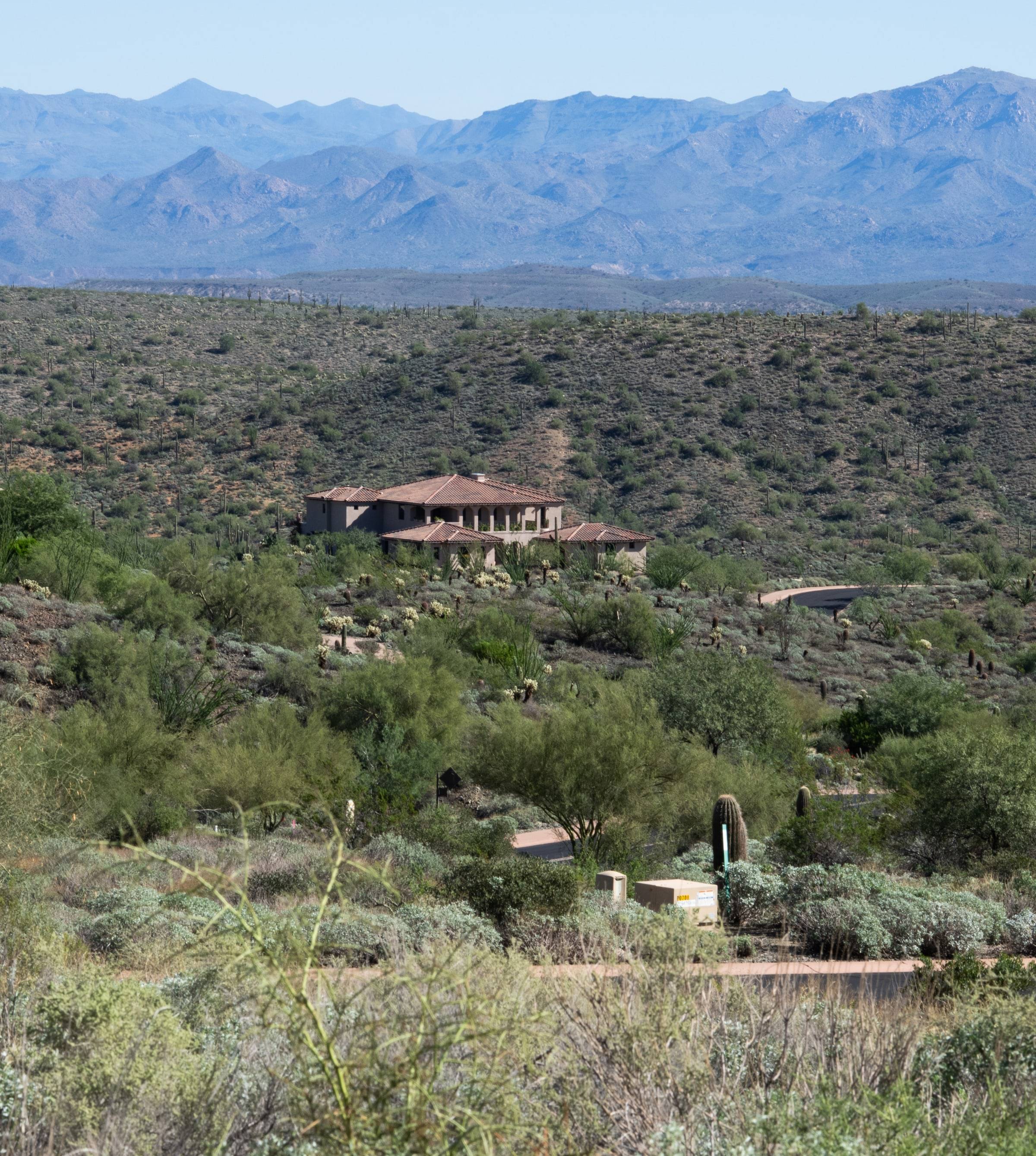 Desert estate nestled in hillside with mountain range backdrop