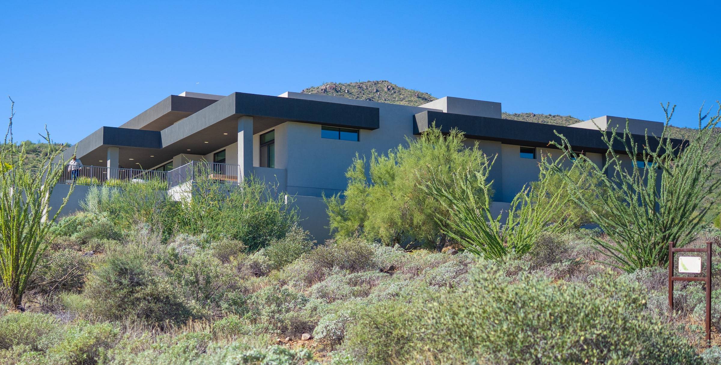 Modern flat-roof home with dark overhangs and desert hillside