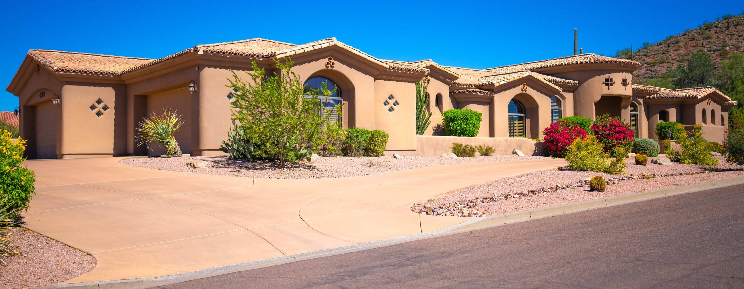 Spanish-style estate with arched entry and desert garden